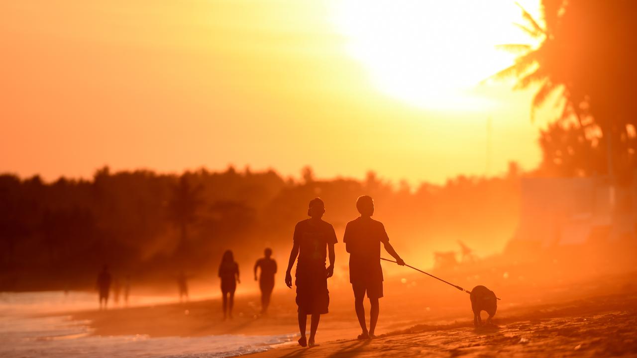People walk along the sand as the sun sets in Bali (file image)