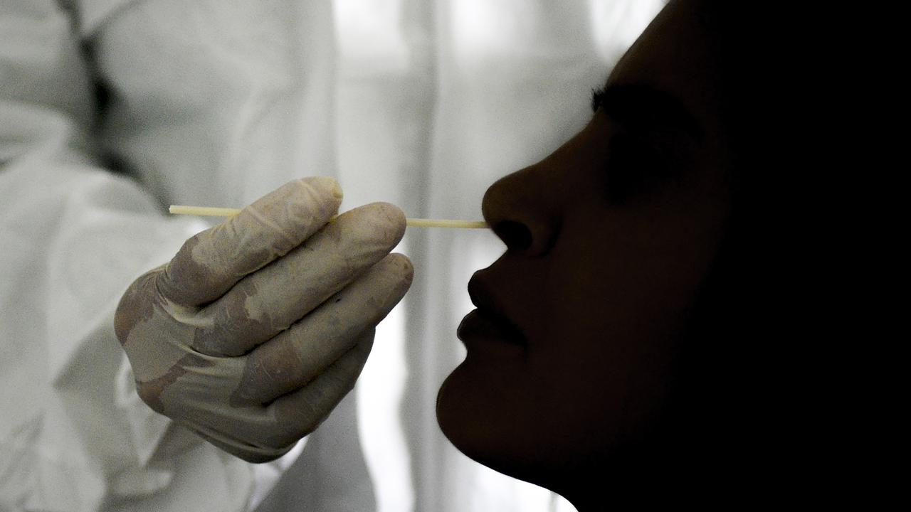 A doctor takes a nasal swab sample to test for COVID-19.