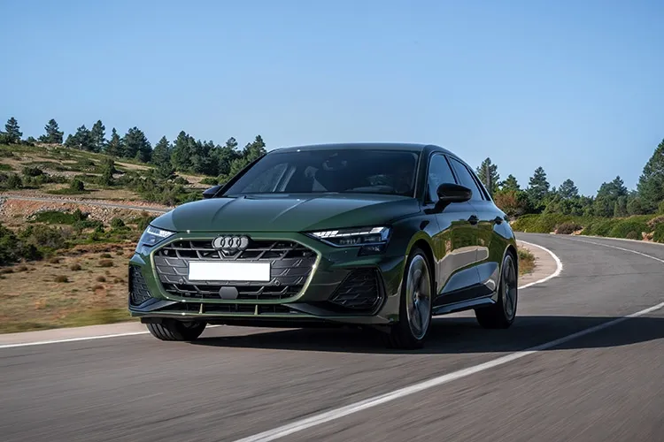 A green Audi driving down a country road.