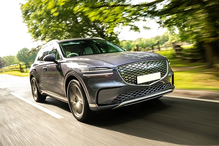 Grey Genesis Gv70 Electric Estate driving down a road