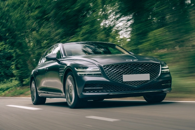 Grey Genesis G80 Electric Saloon driving along a country road