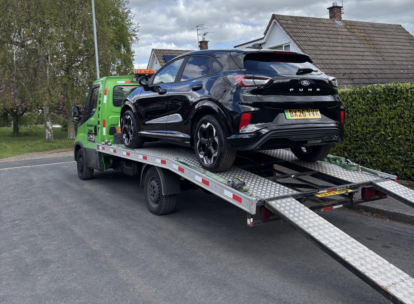 A black Ford Puma Gen-E being delivered outide Renee's house on a tow truck.