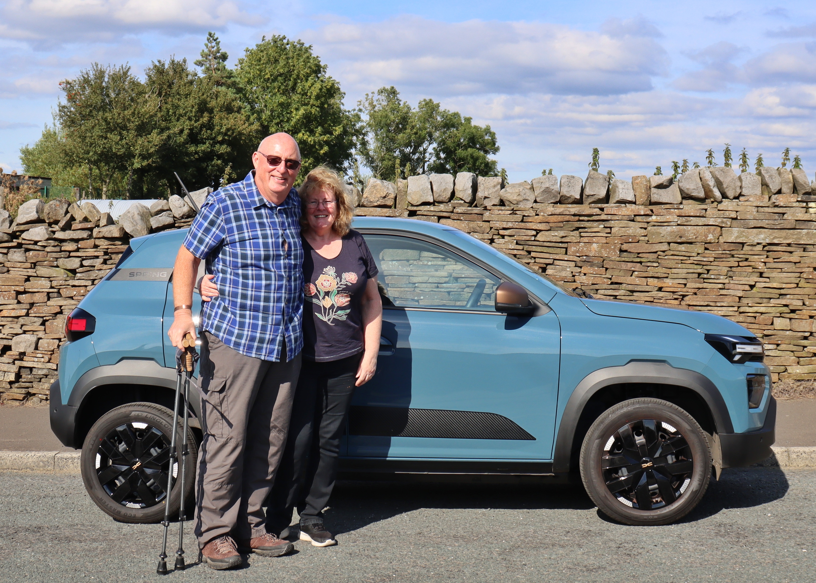 Andy and his wife stood in front of their turquoise Dacia Spring.