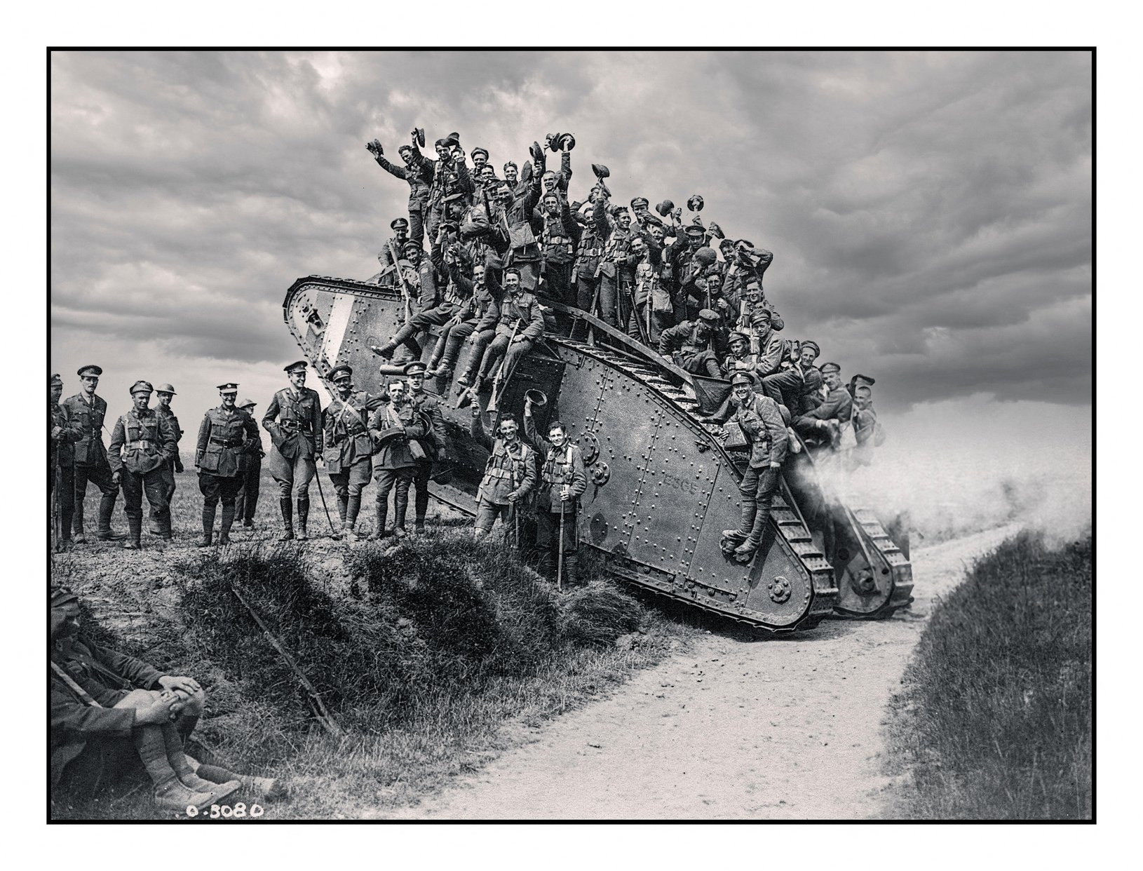 A tank halfway up a hill with soldiers stood on top and around it posing for a photograph.