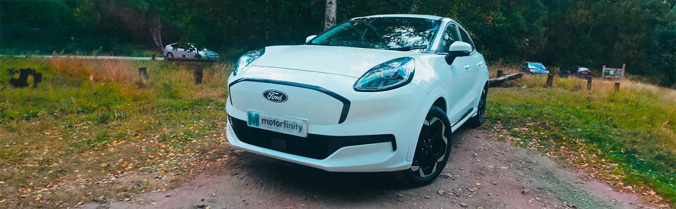 A white Ford Puma Gen-E parked in a woodland car park.