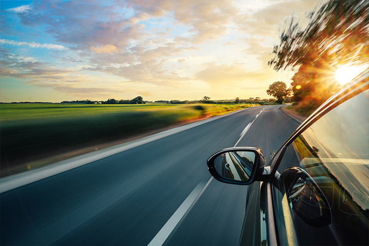 A car driving along a scenic country road while the sun is setting