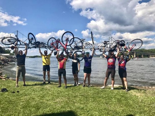 A group of cyclists holding their bikes up.