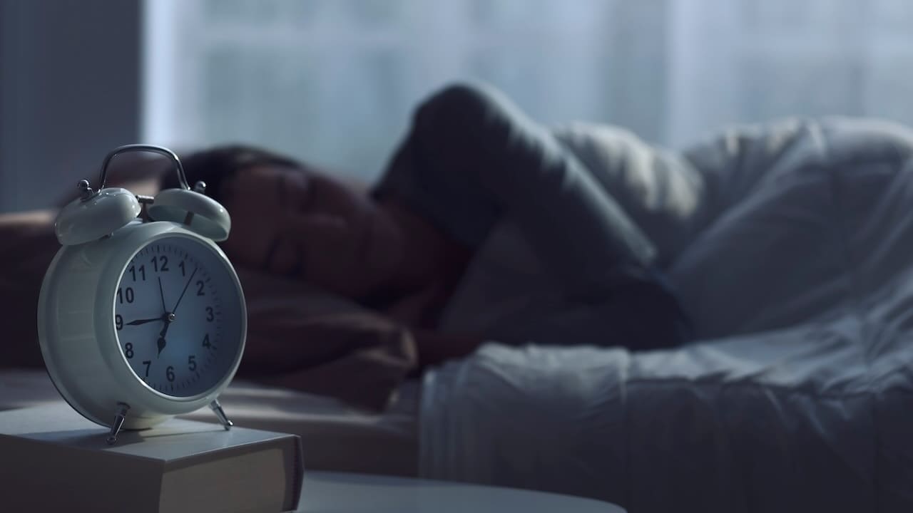 夜に眠る人と目覚まし時計