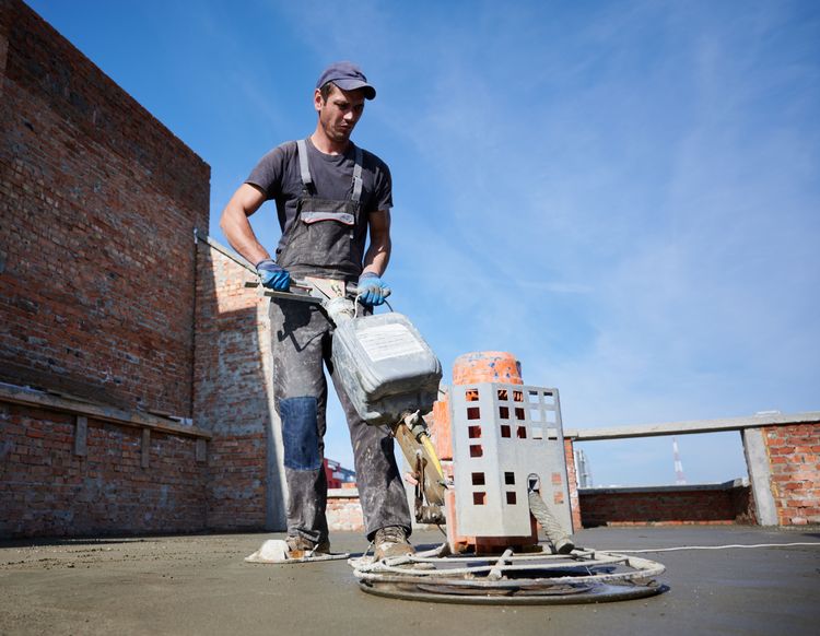 worker_using_power_trowel_machine_at_construction_site