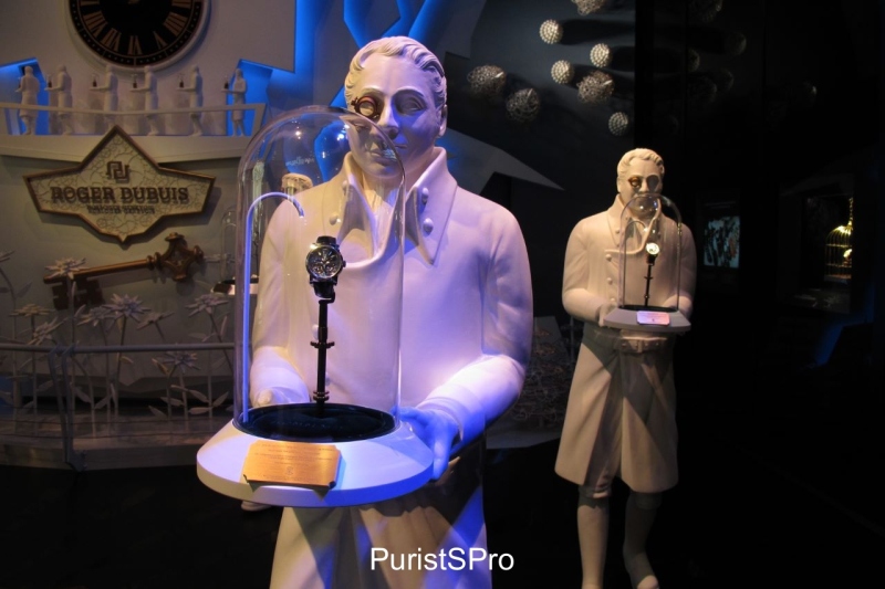 Novelties showcased in glass displays carried by statues (of watchmakers with loupes?) - impressive displays!