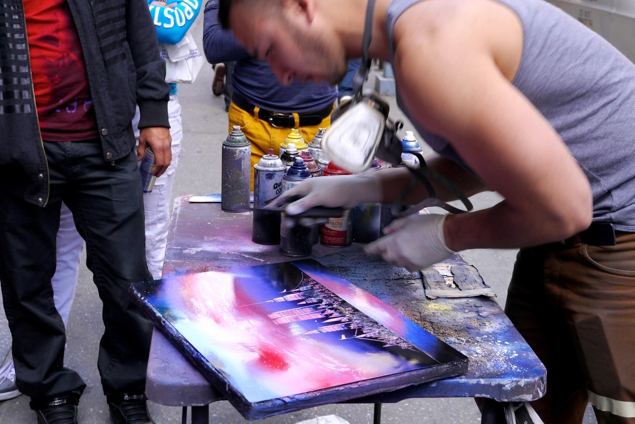 Street Artist usig spray paint and spatula to create painting