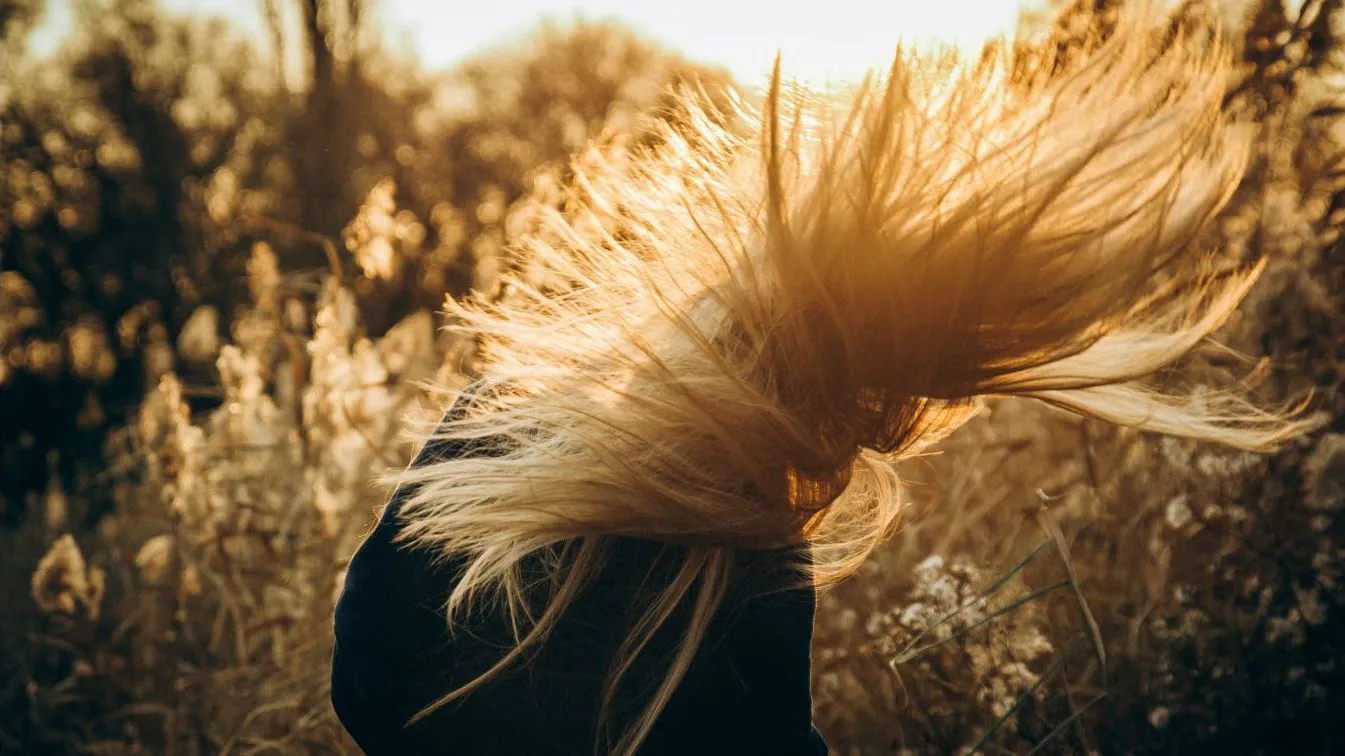 Eine Frau mit langen blonden Haaren, die vom Wind zerzaust werden