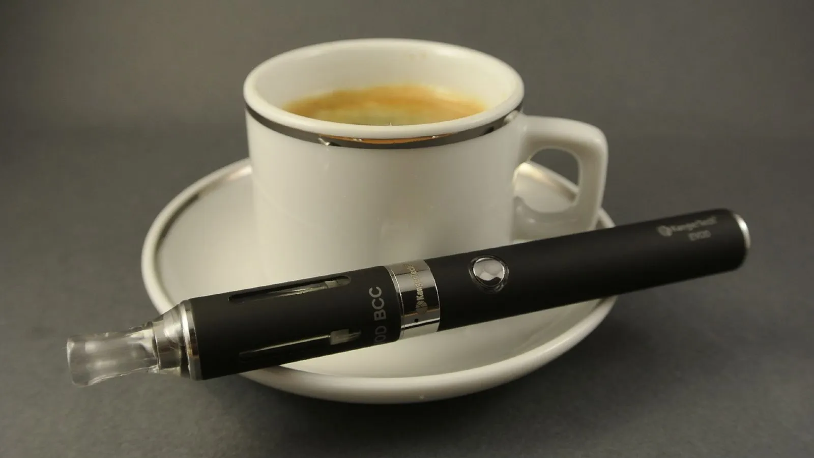 Kaffeetasse, auf dem Unterteller liegt eine E-Zigarette