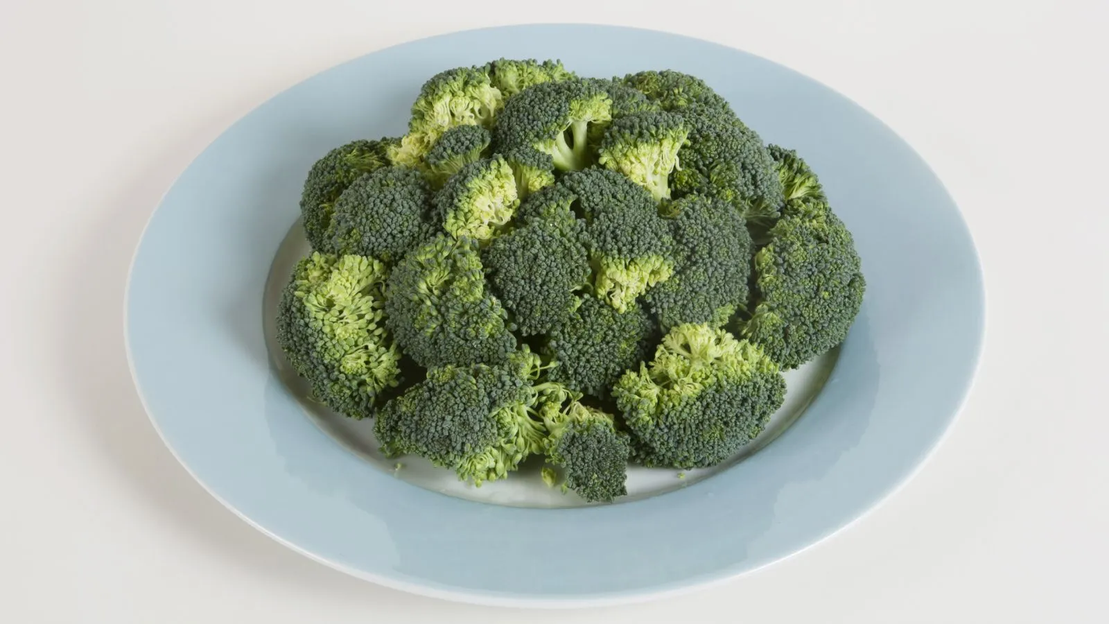 Vielr Broccoliröschen liegen auf einem blauen Teller 