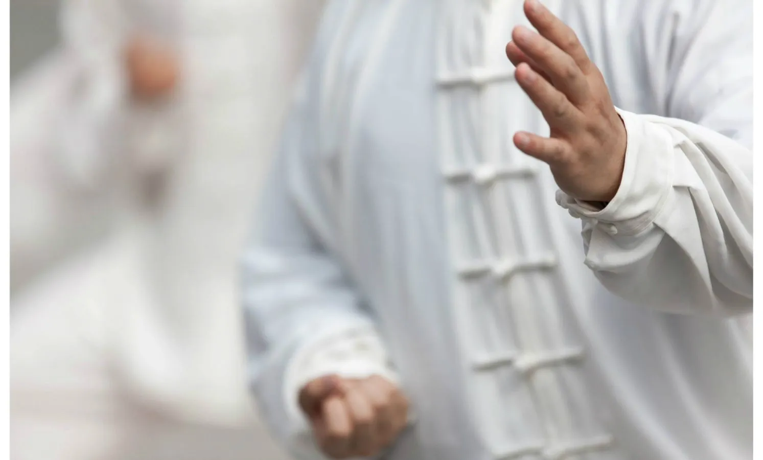 Ein Mann in weissem Gewand trainiert Tai Chi