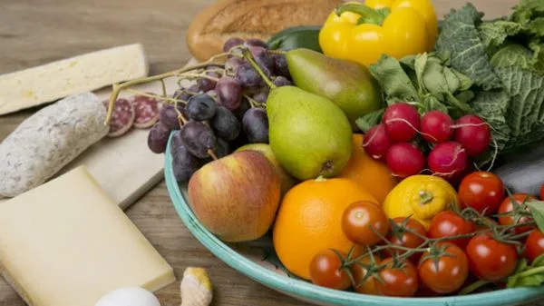 Obst und Gemüse in einem Teller, daneben Käse und Wurst