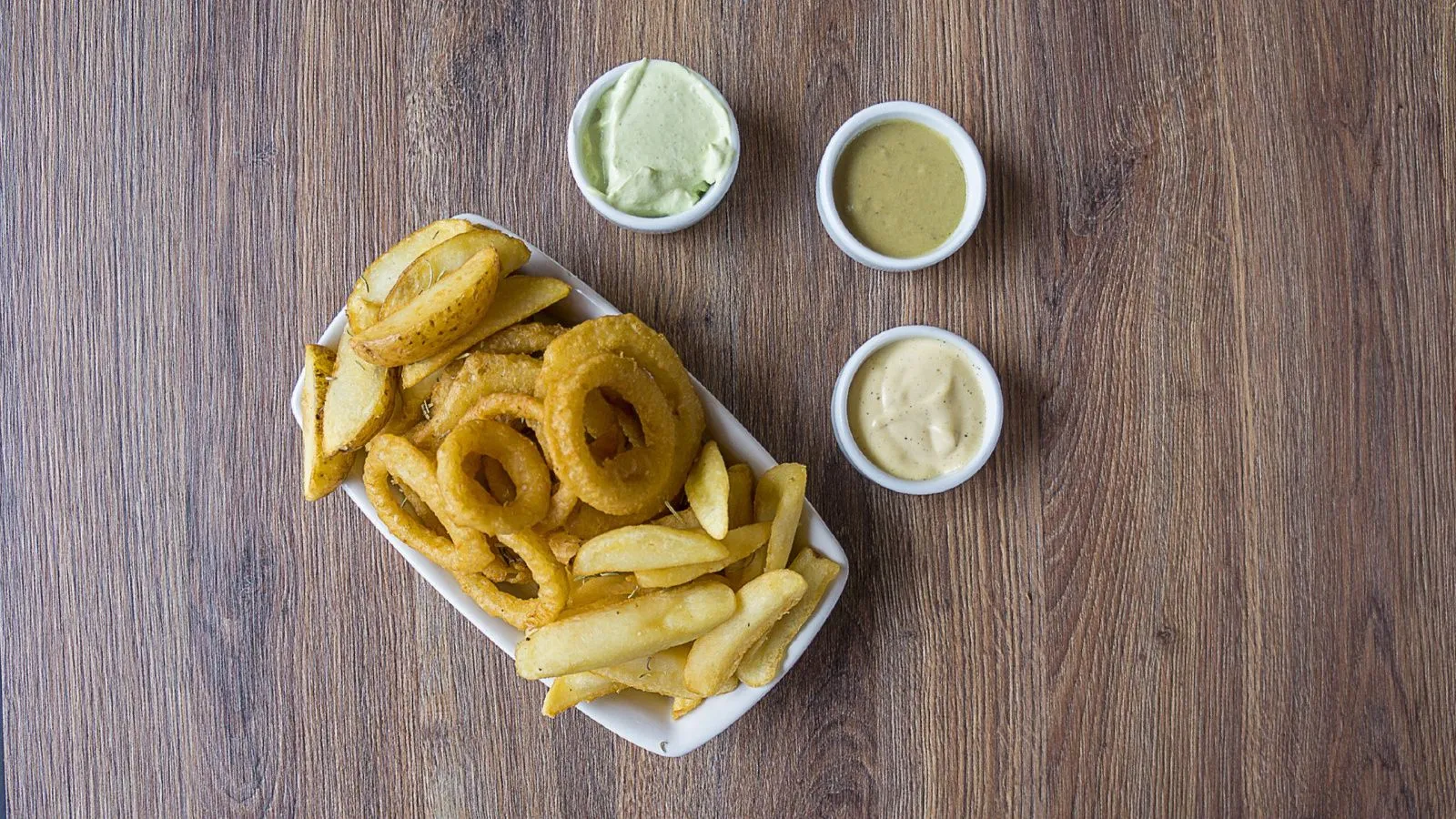 Frittiertes Fast-Food in einer Schale, daneben Saucen in kleinen Schälchen