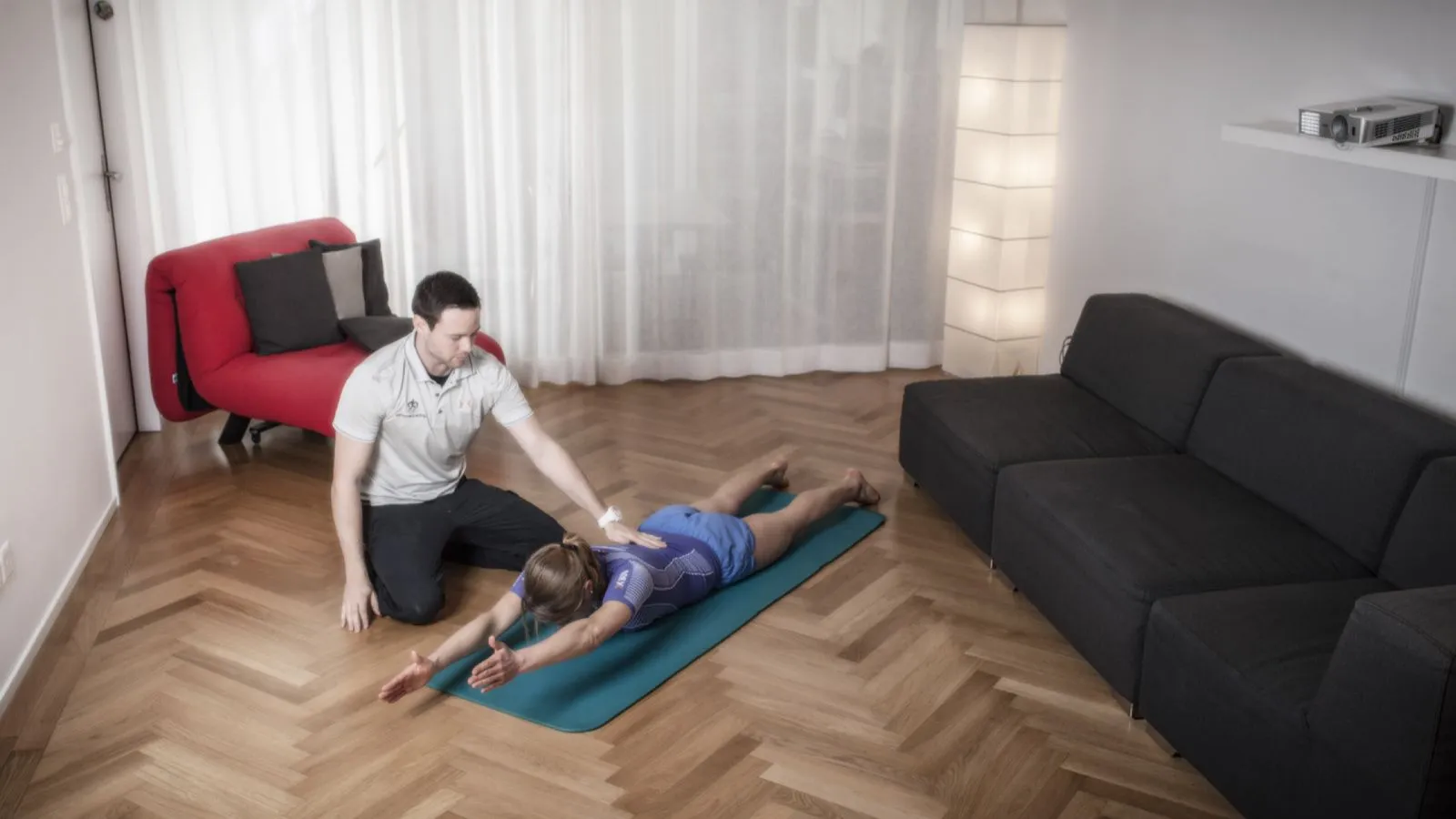 Fitnesstrainer instruiert Schülerin in der Ausführung des Rumpfhebers.