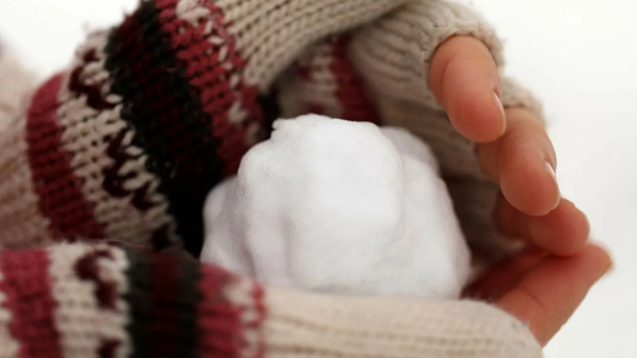 Hände in Fingerlosen Handschuhen, die einen Schneeball formen