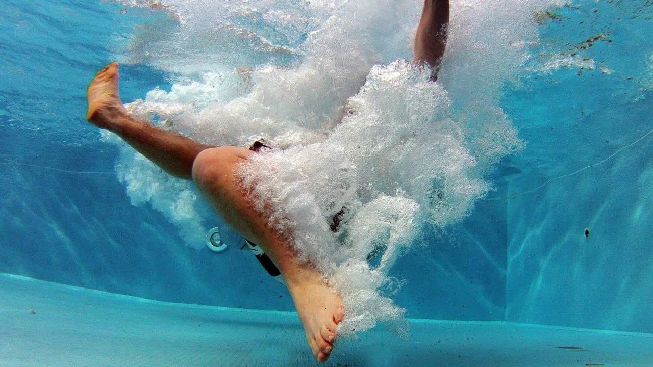 Unter-Wasser-Foto von jemanden, der in einen Swimmingpool springt