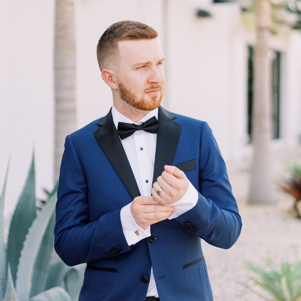 Greg in a suit and adjusting his cuff links