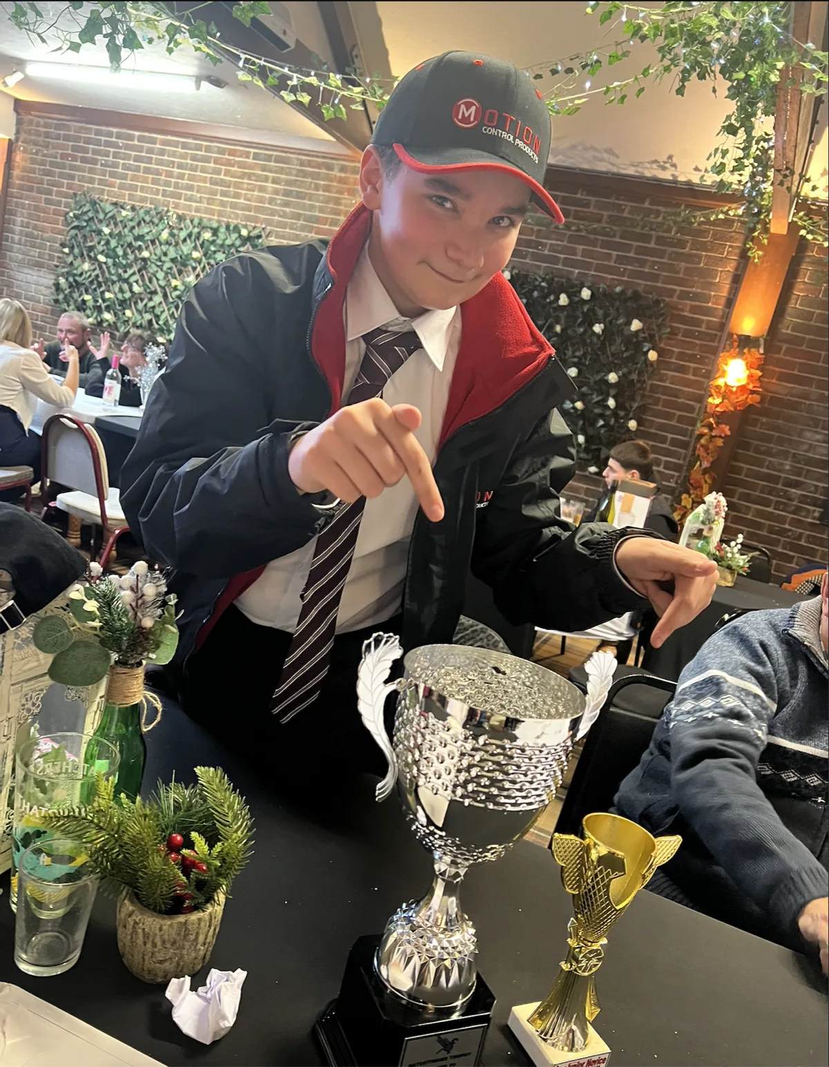 Young kart racer pointing at trophies at an awards ceremony