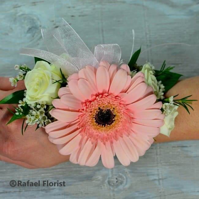 Wrist corsage of pink gerbera daisy and white spray roses