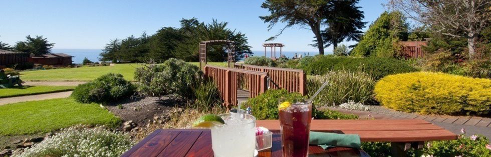 drinks on an outside table overlooking lawn with ocean and cliff view