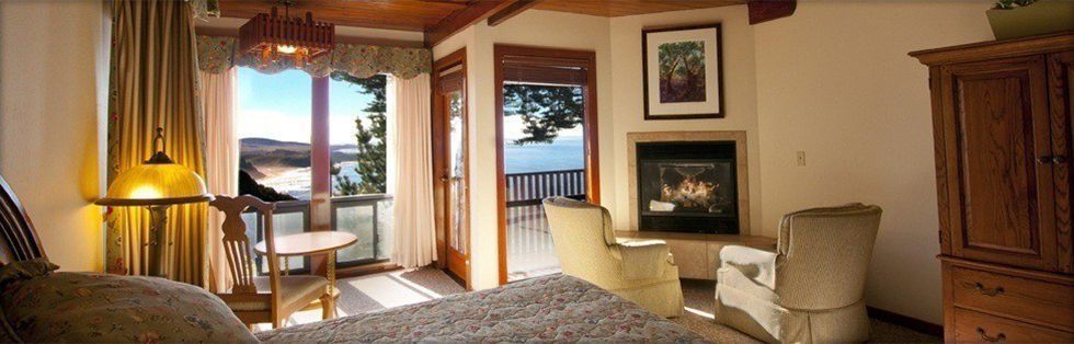 room with bed and chairs next to fireplace with ocean views