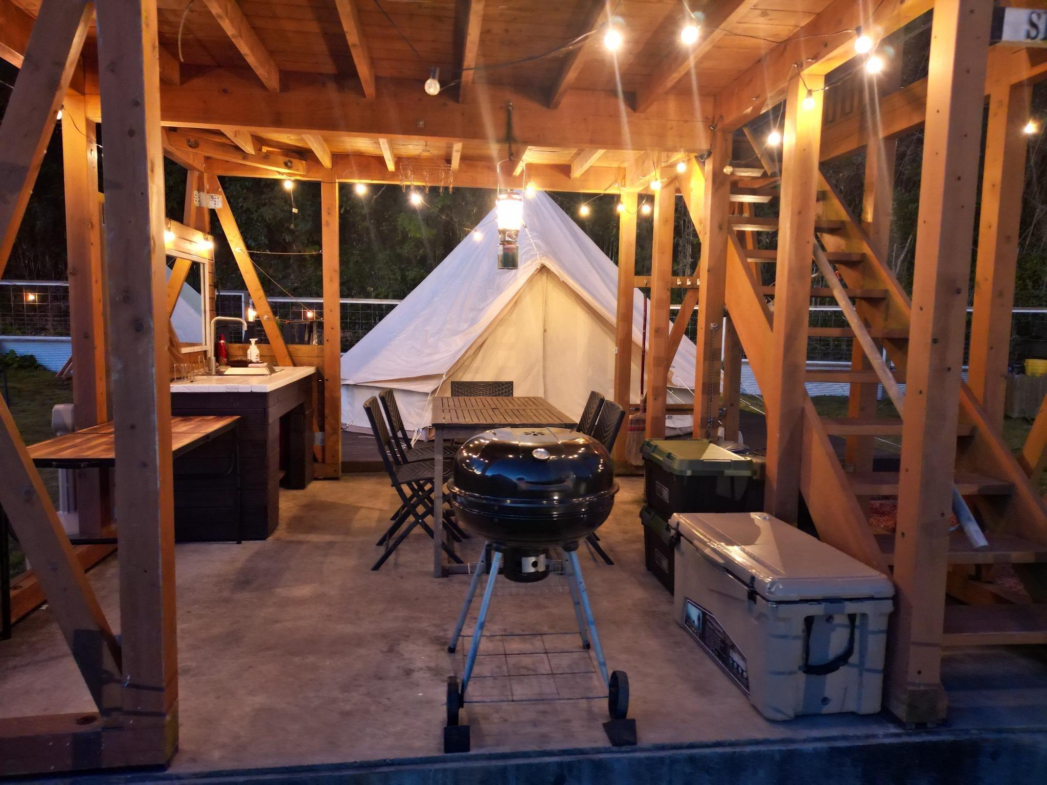 バーベキューデッキはテントに隣接してます。大型のバーベキューコンロ、テーブル、椅子、保冷庫、食器一式、さらに調理台と洗い場まで備えています。