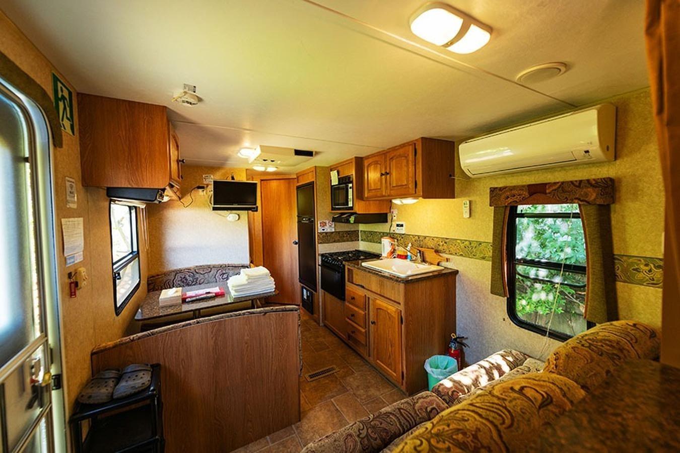 【トレーラーハウス】アメリカから輸入された本場のトレーラーハウス。車内にはエアコン、キッチン、寝具、トイレ、シャワーなど必要なものは全て揃っています。室内にいると車であることを忘れてしまう快適なプライベート空間です。 外部テラスにはこのお部屋タイプのみ使用できるBBQグリルもご用意。 1棟だけの特別なトレーラーハウスで、ご家族やグループでグランピングを楽しむのに最適です。