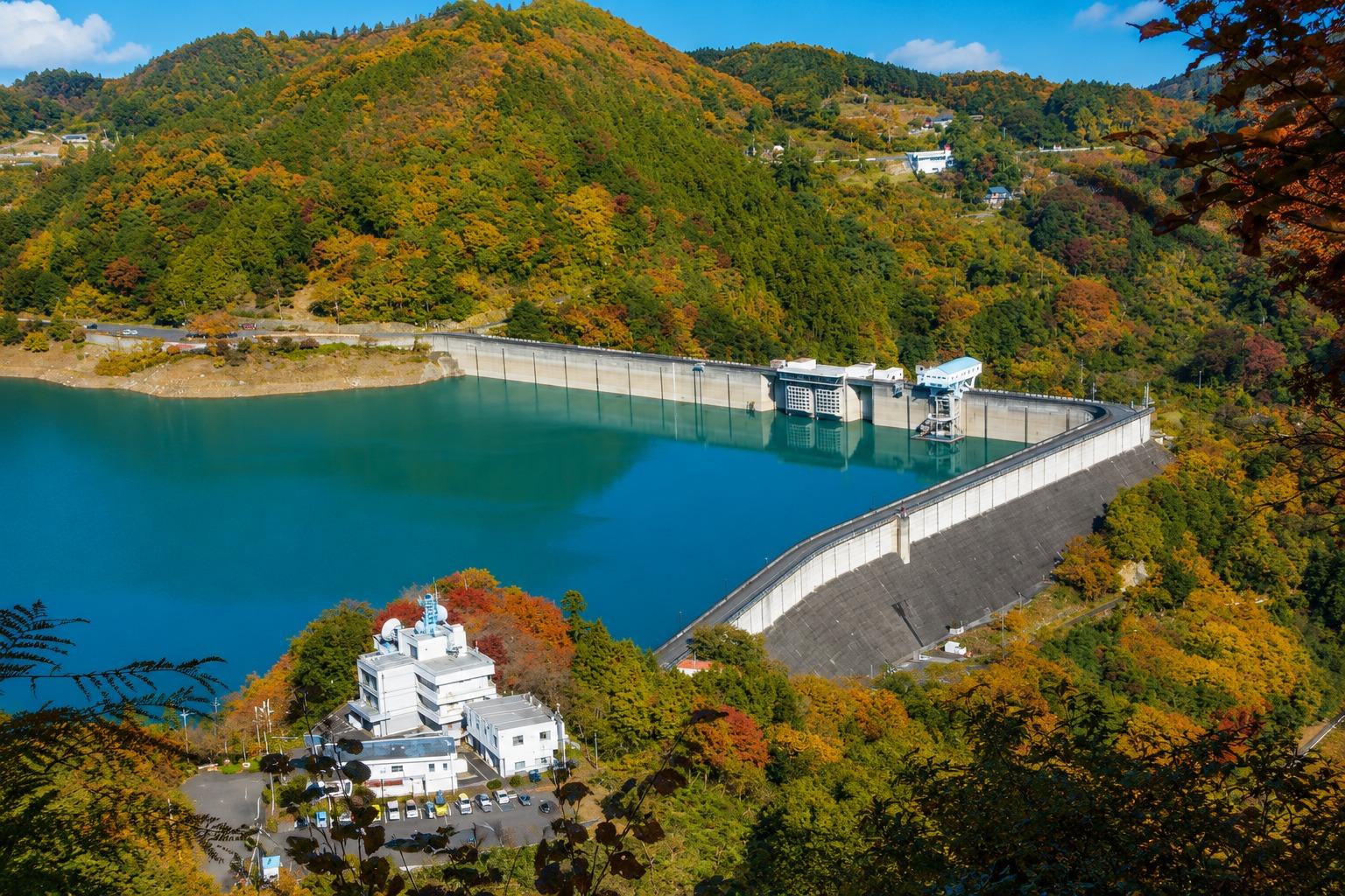 神流湖の美しい景観をつくり出す下久保ダムは、群馬県と埼玉県にまたがる利根川水系最大級の重力式コンクリートダムです。雄大なダム湖と四季折々に色づく山々が織りなす景色は、訪れる人を魅了します。展望スポットからは迫力あるダムの全景を一望でき、春の新緑、夏の深緑、秋の紅葉、冬の澄んだ空気と、季節ごとに異なる美しさを楽しめます。