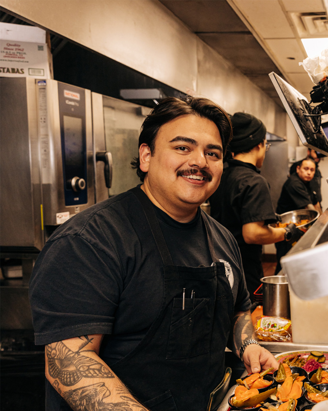 Jonathan Zaragoza stands in a kitchen smiling at the camera.
