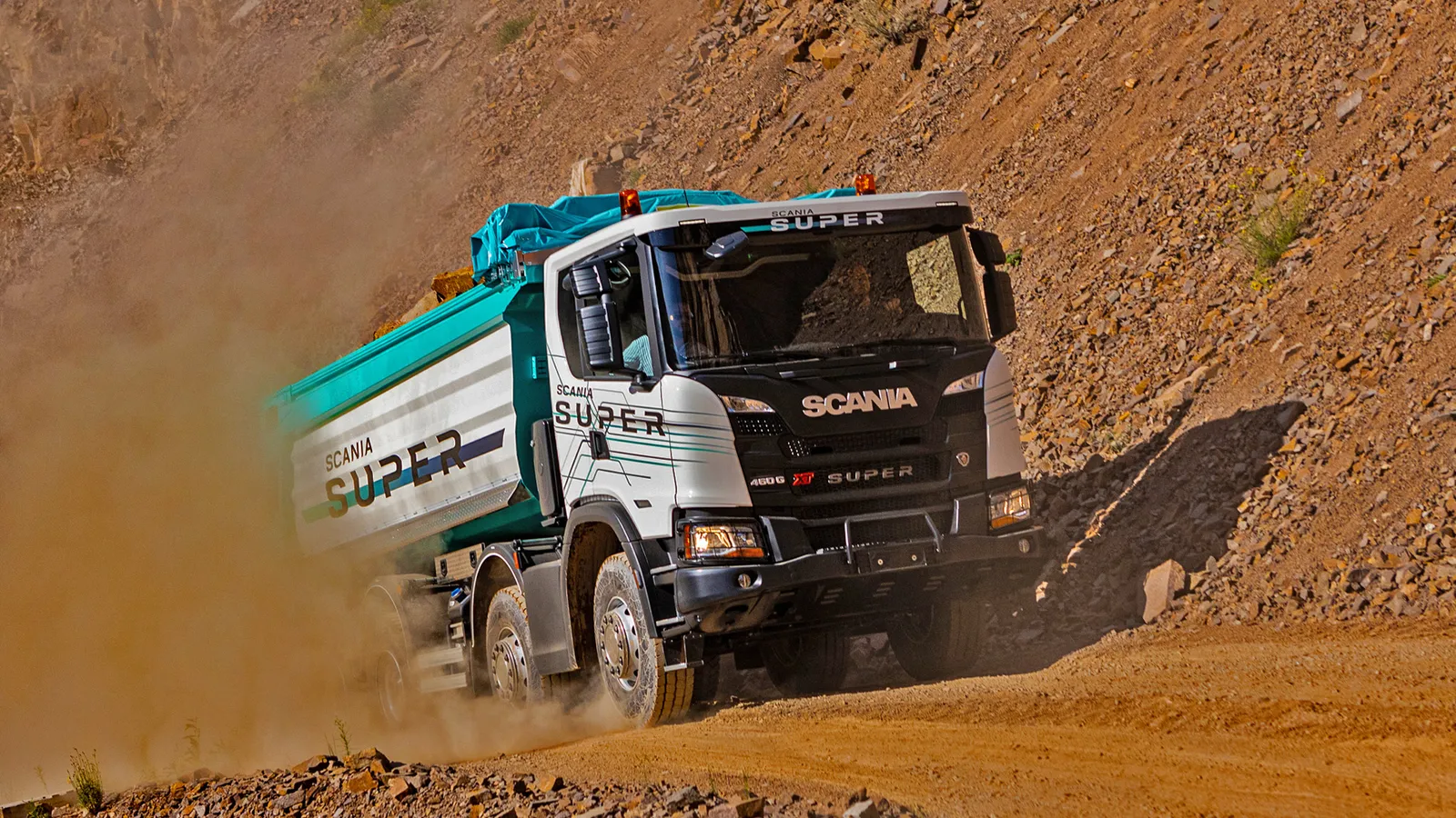 Un camion Scania Super che guida su una strada sterrata.