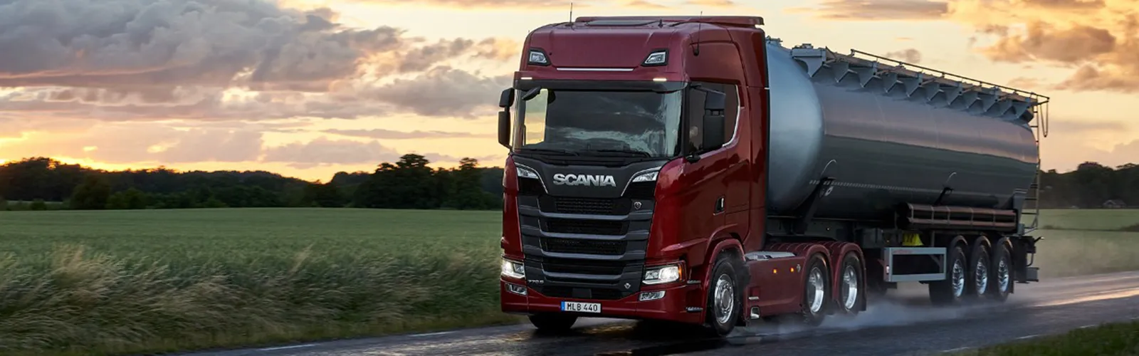 Camion Scania su strada di campagna al tramonto.