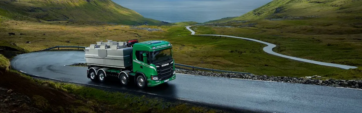 Un camion verde Scania che percorre una strada di montagna.