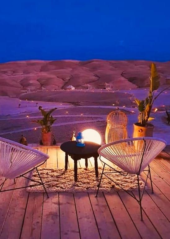 two chairs and a small desk with the view of mountains at the agafay luxury camp in marrakech 