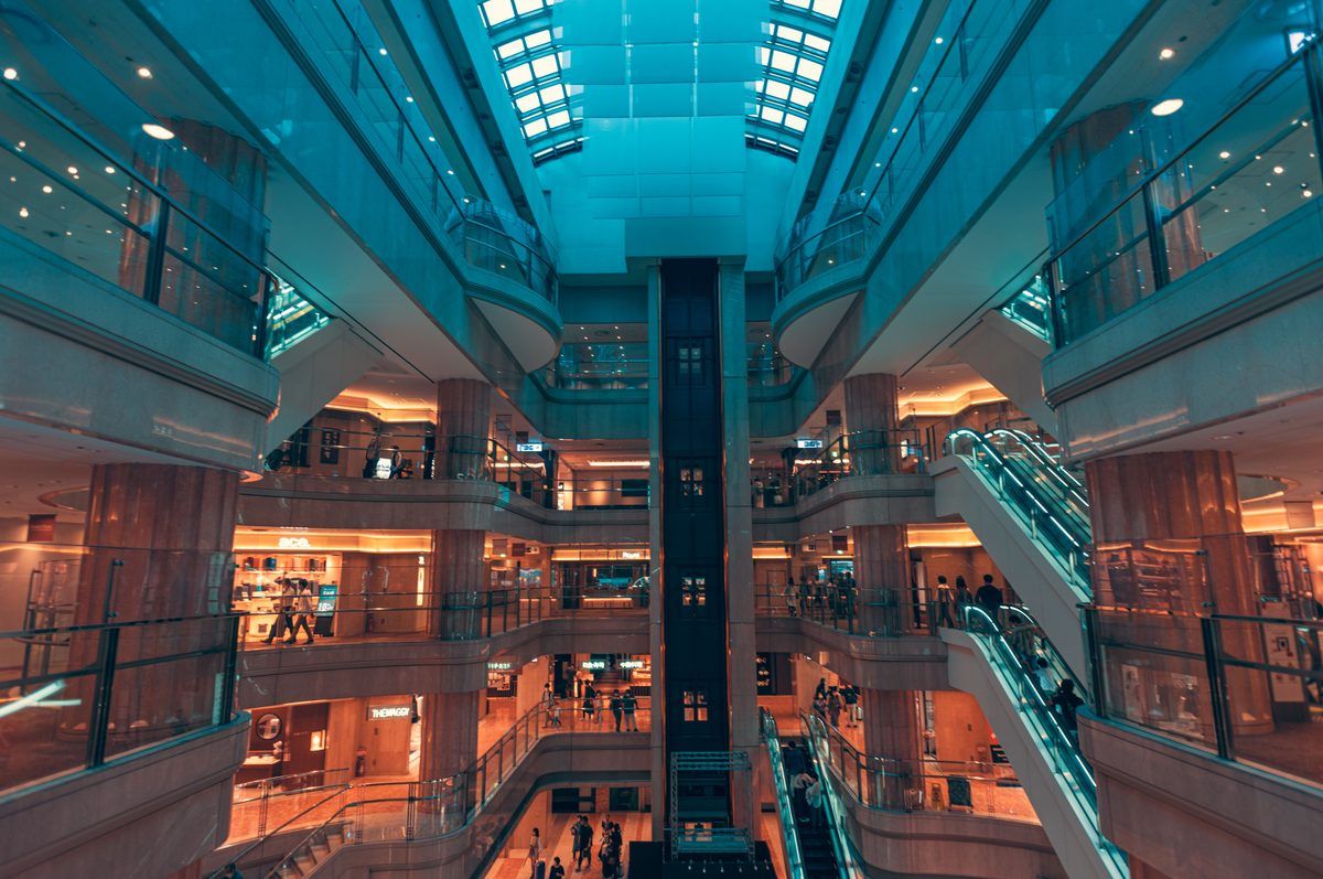 Multi-level atrium with escalators and shops, lit in teal and orange.