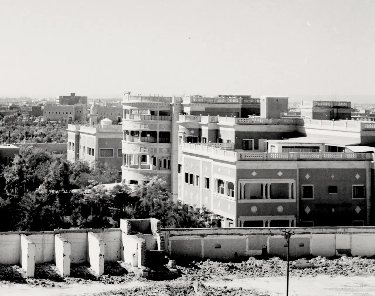 Black and white city overview featuring buildings with curved balconies and scattered trees.