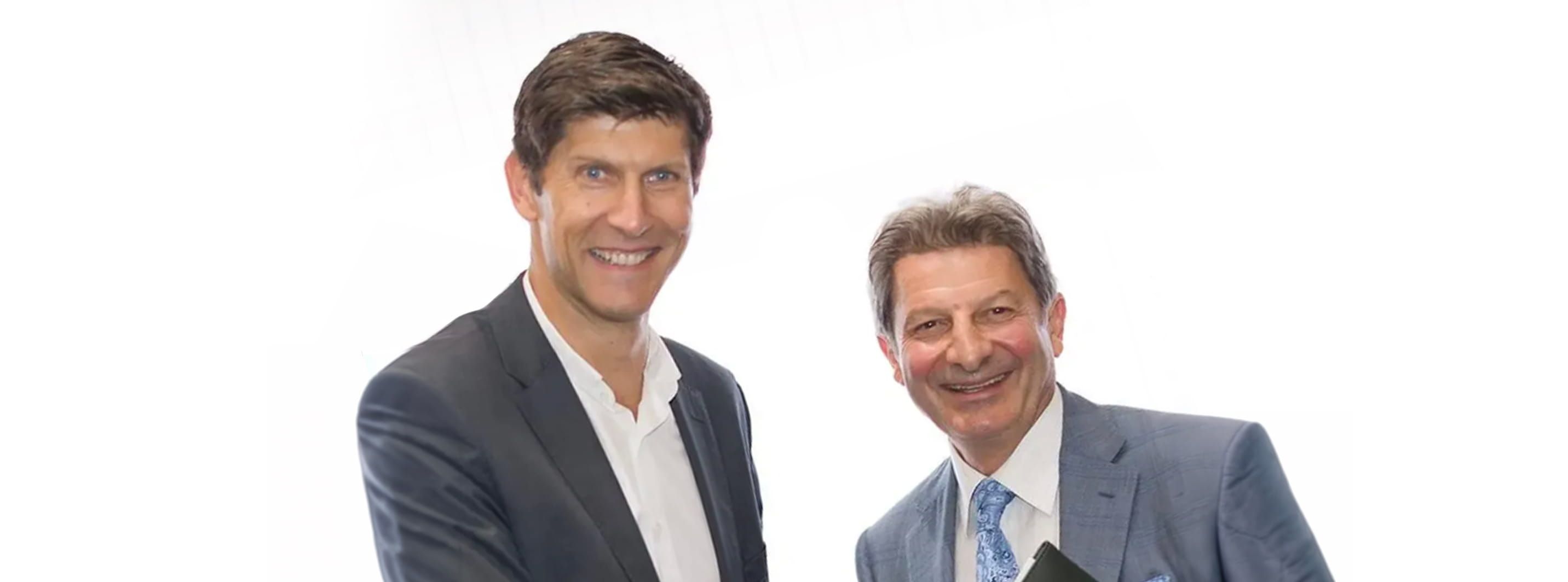 Two smiling men in business attire stand side-by-side against a white background.