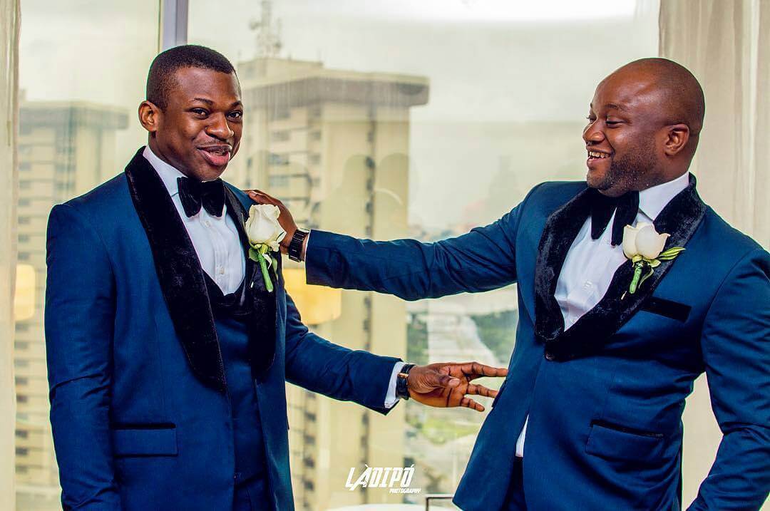 Black groom and his groomsman wearing boutonieres and blue suits