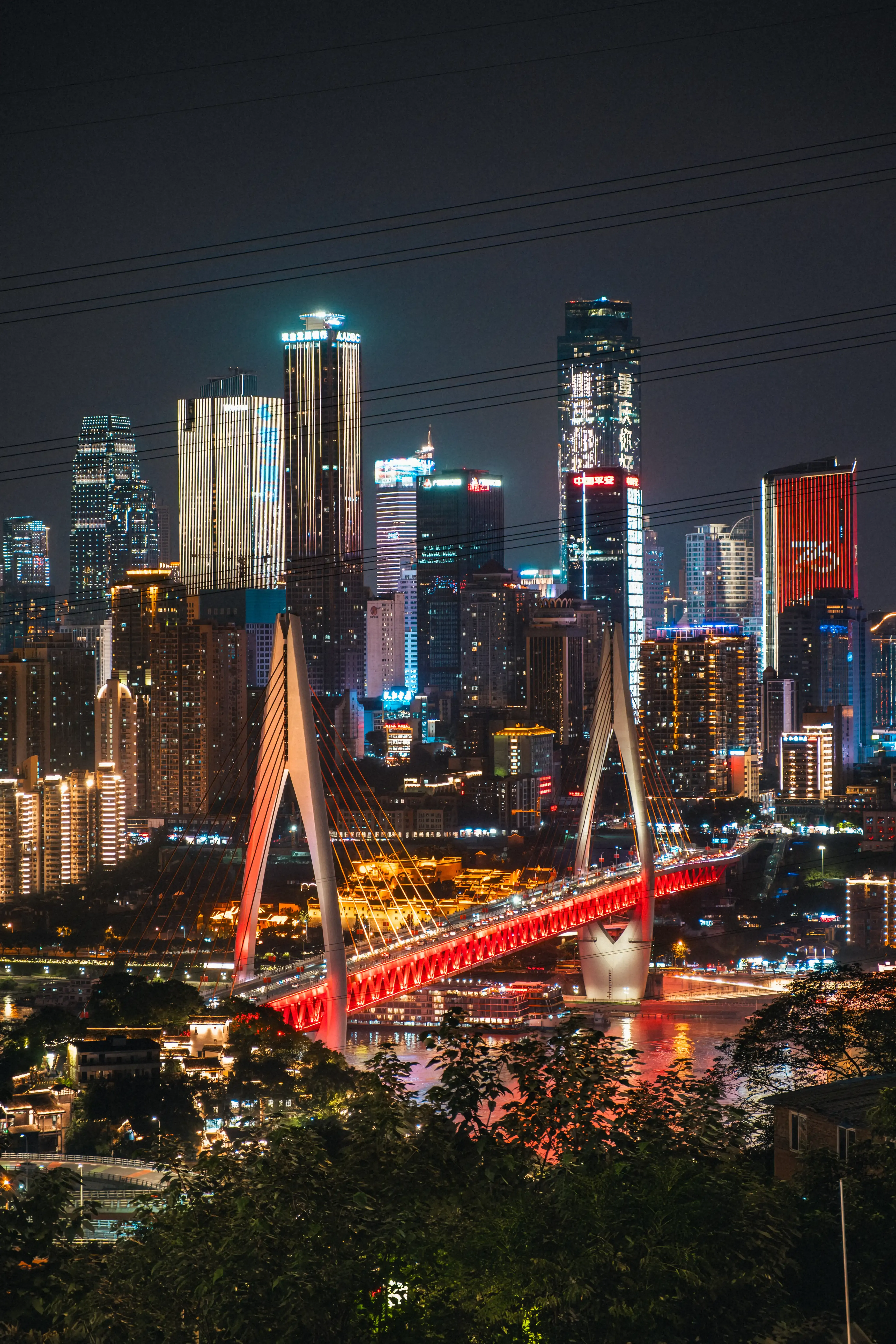 Vue panoramique nocturne de Chongqing avec son pont rouge majestueux depuis une colline
