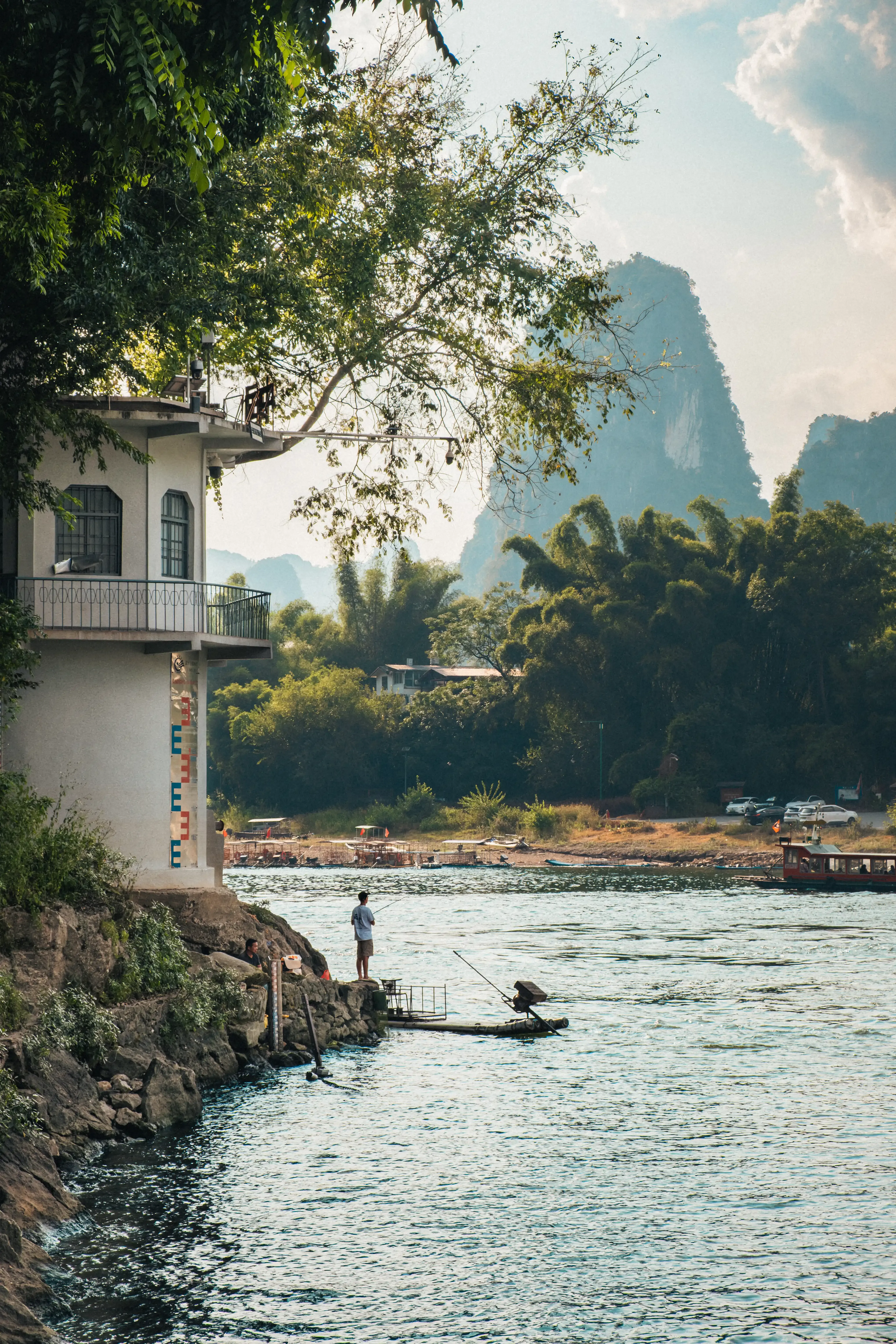 Pêcheur debout sur un radeau en bambou près de la rive, rivière Li, Yangshuo