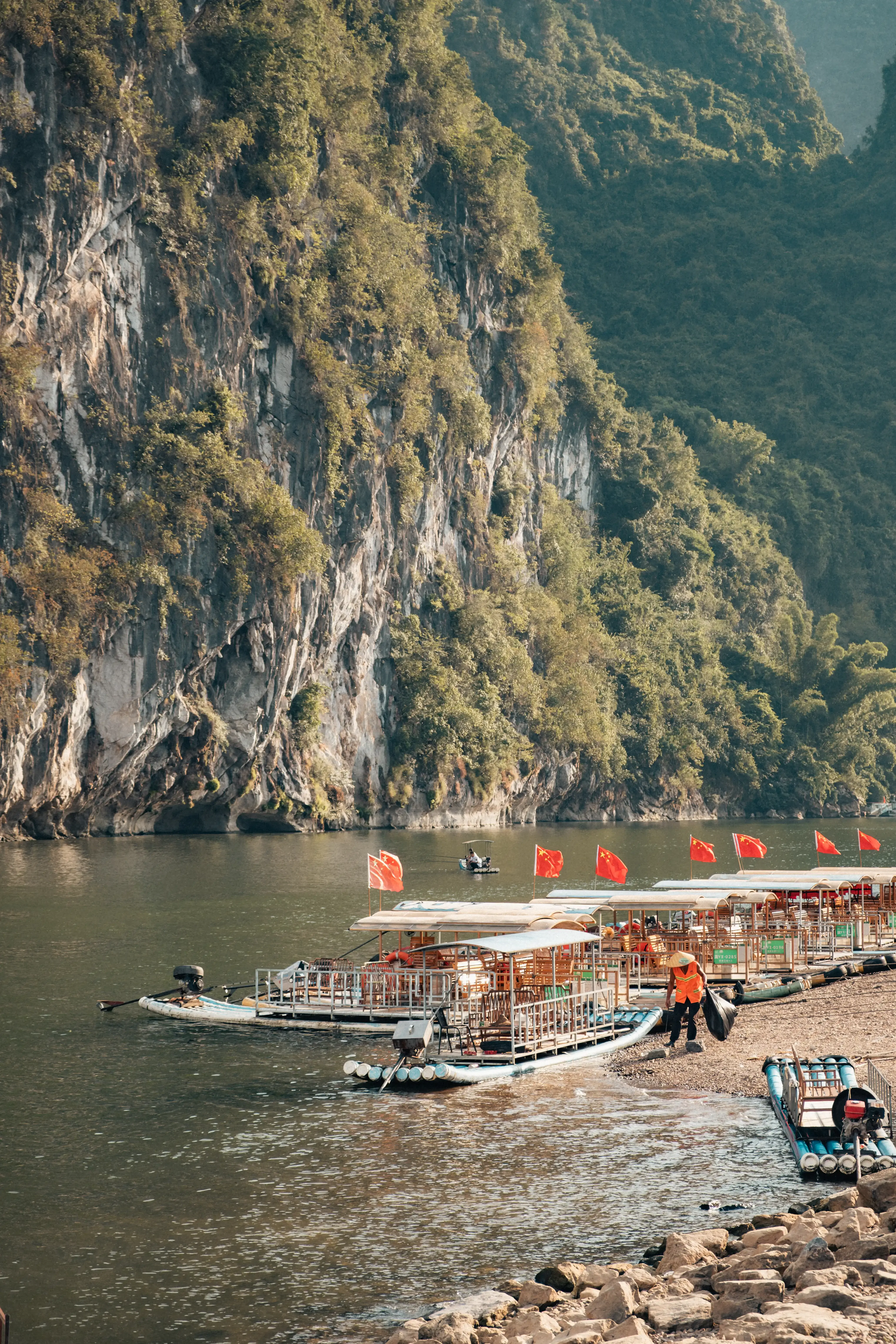 Bateaux traditionnels amarrés au bord de la rivière Li sous une falaise karstique couverte de végétation, Yangshuo