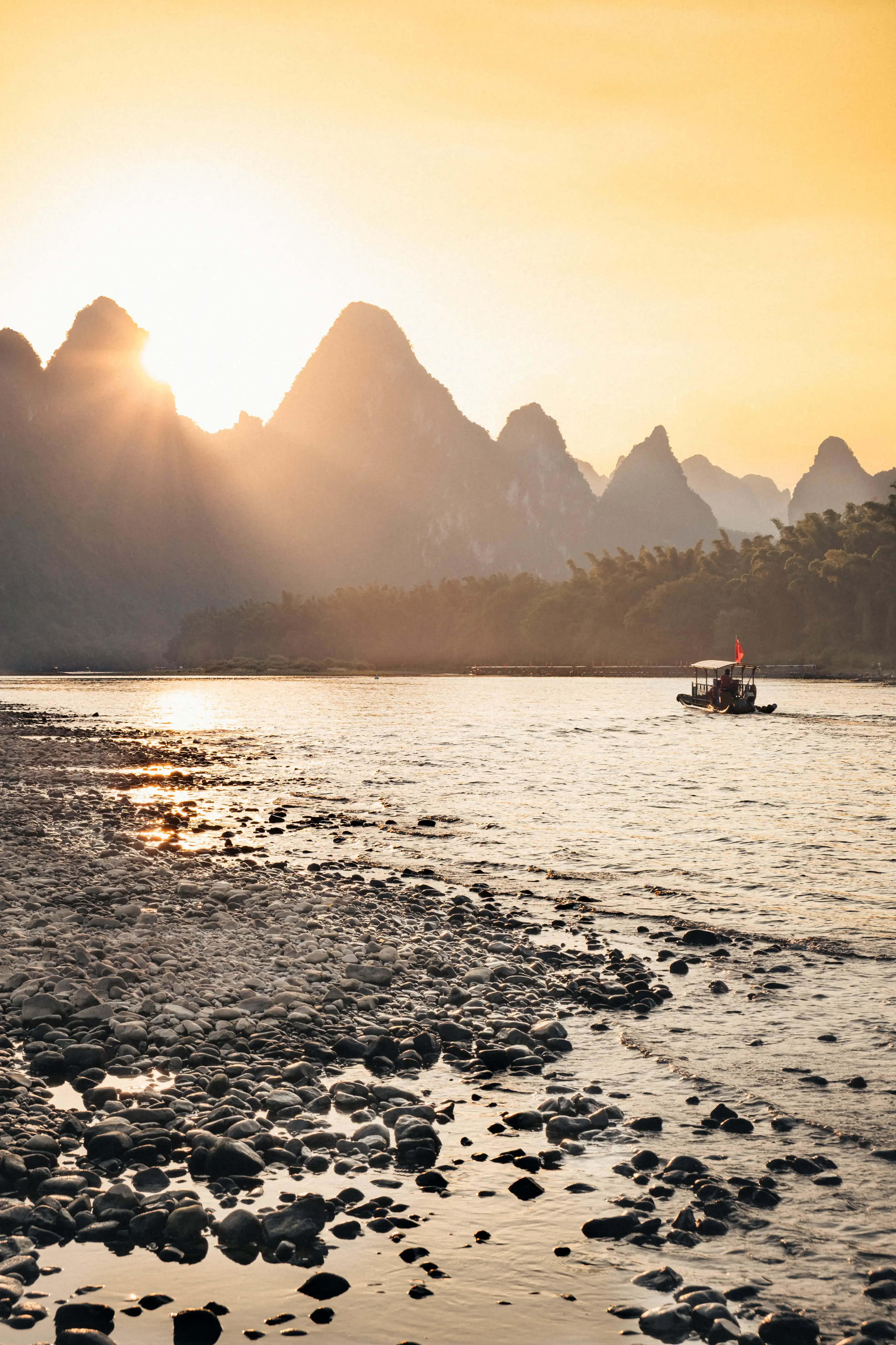 Rayons de soleil dorés perçant entre les pics karstiques de Yangshuo, embarcation sur la rivière Li, Guangxi, Chine