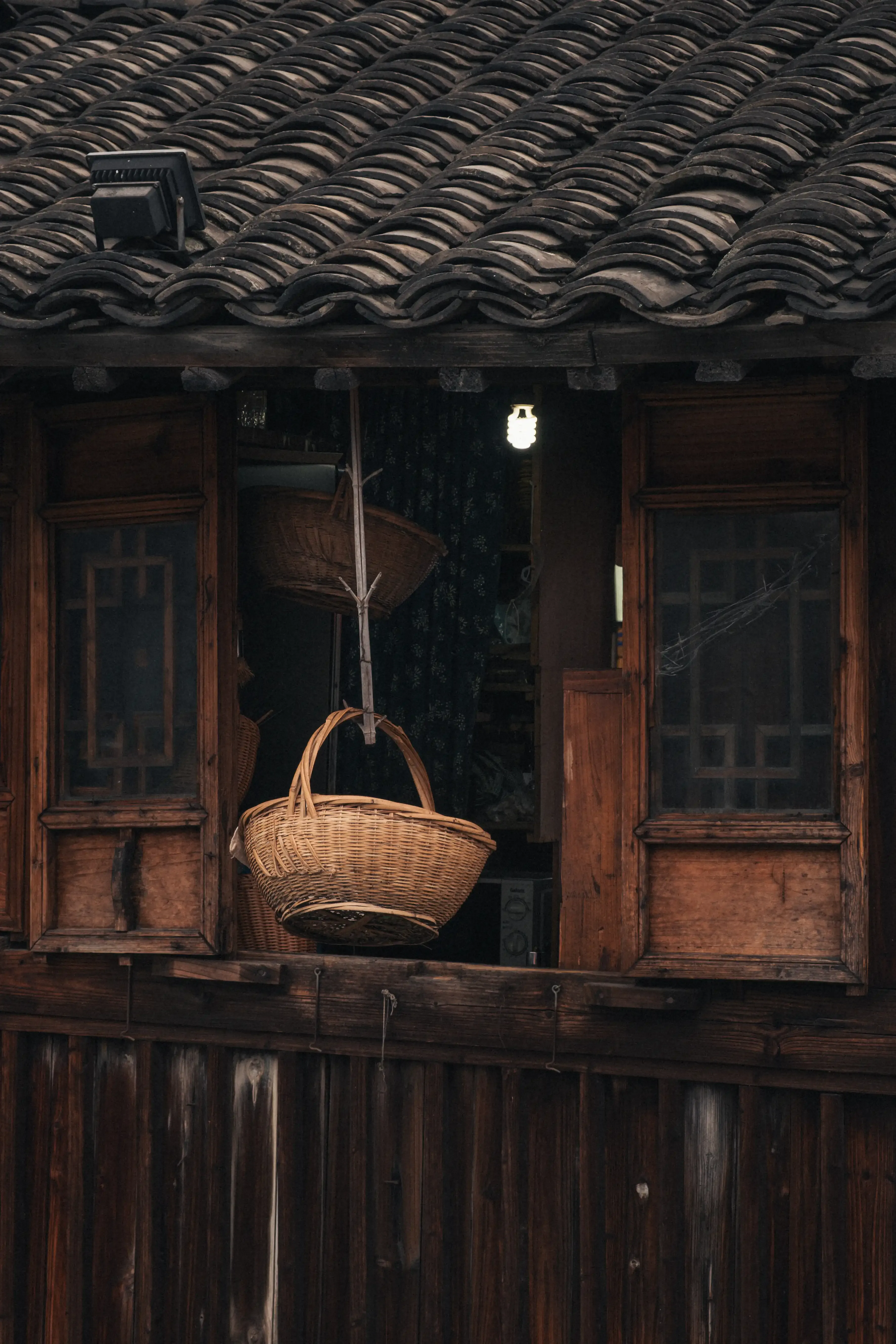 Panier en osier suspendu à une fenêtre traditionnelle en bois sculpté dans la pénombre