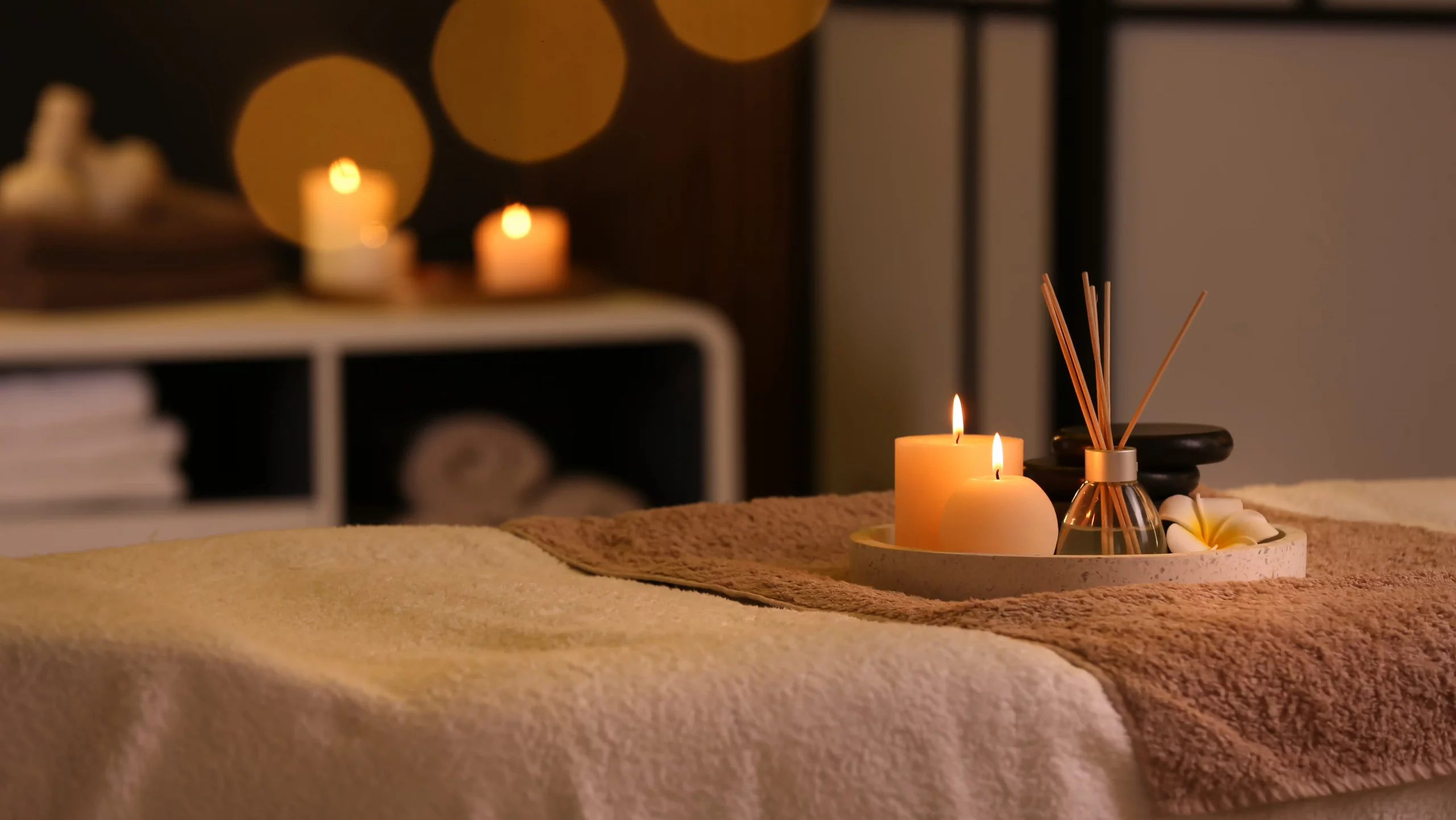 Close up of a trail with light on candles and flavoring on top of a bed