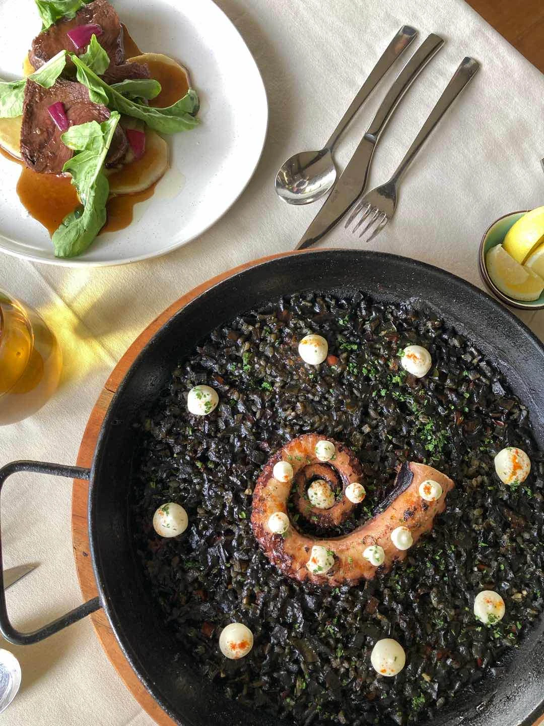 Grilled US Rib-Eye Steak with Marble Potatoes, Octopus and Blank Ink Paella