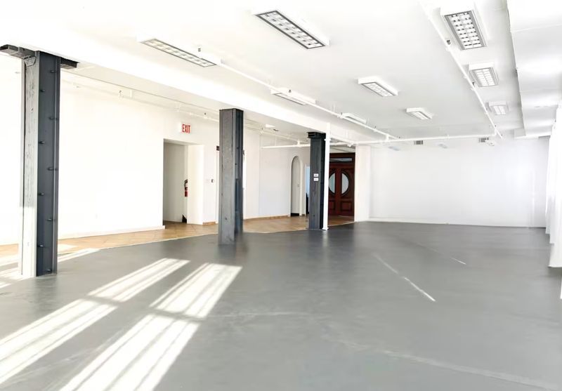Open industrial loft interior with full-length windows at Pitkin Lofts in East New York, Brooklyn
