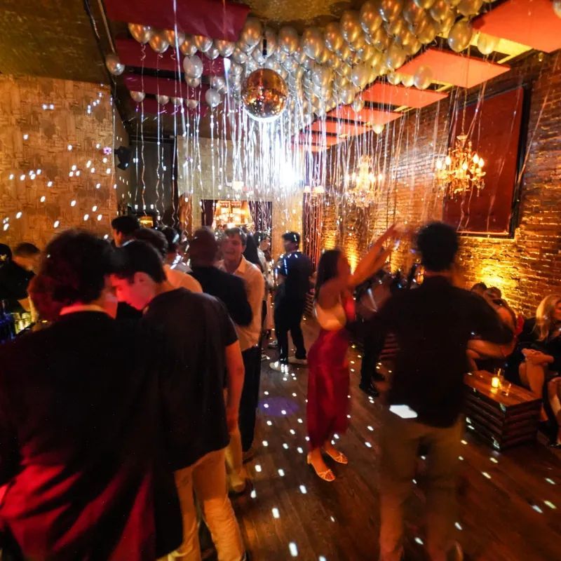 Warmly lit bar area at Velvet Brooklyn in Williamsburg with exposed brick and vintage chandeliers